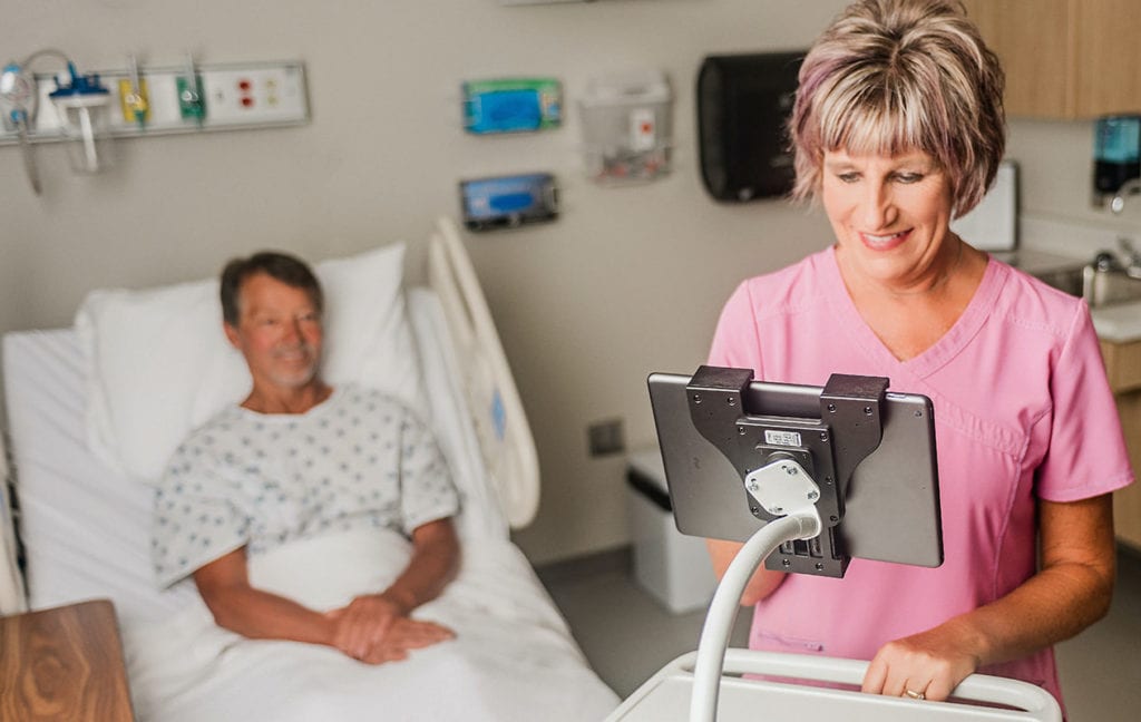 Smiling healthcare worker on a tablet using a Moffatt flexarm