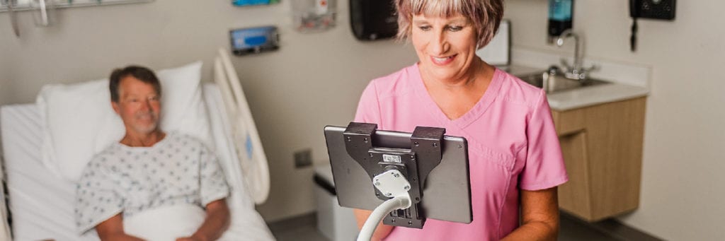 Smiling healthcare worker on a tablet using a Moffatt flexarm