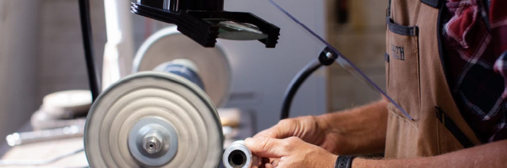 Man polishing metal while using a flex arm protective shield