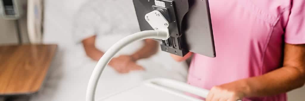 Flex arm with vinyl coating in a medical setting holding up a tablet that nurse is using